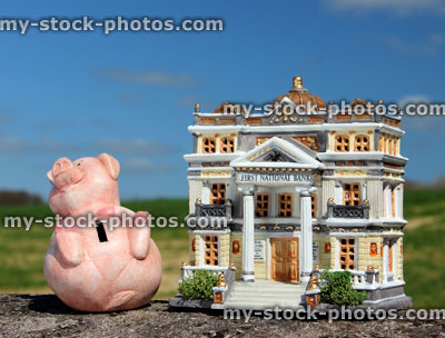 Stock image of model bank and a piggy bank, against blue sky