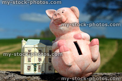Stock image of cheerful piggy bank and small home / dolls house