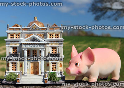 Stock image of model bank and a piggy bank, against blue sky