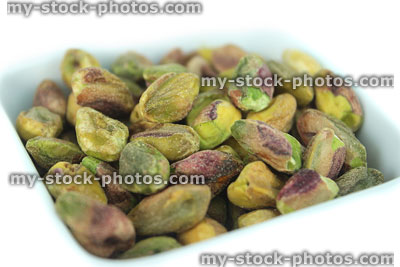 Stock image of shelled pistachio seeds / nuts in white dish, health benefits