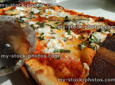 Stock image of cheese and tomato pizza in Italian restaurant, pizza wheel cutter