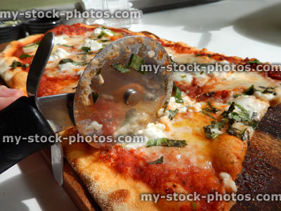 Stock image of cheese and tomato pizza in Italian restaurant, pizza wheel cutter