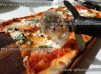 Stock image of cheese and tomato pizza, Italian restaurant, pizza wheel cutter / cutting