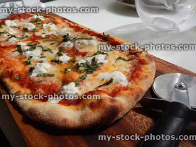 Stock image of cheese and tomato margherita pizza, Italian restaurant, pizza wheel cutter / cutting