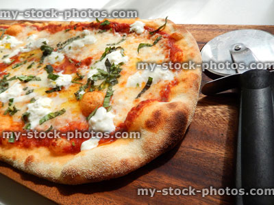Stock image of cheese and tomato margherita pizza, Italian restaurant, pizza wheel cutter / breadboard