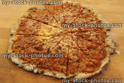 Stock image of homemade margherita pizza cut into slices, wooden board