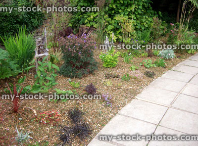 Stock image of herbaceous flower border in garden, bark mulch, paving slabs