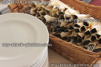 Stock image of stacks of white plates at buffet, cutlery (knifes / forks / napkins)