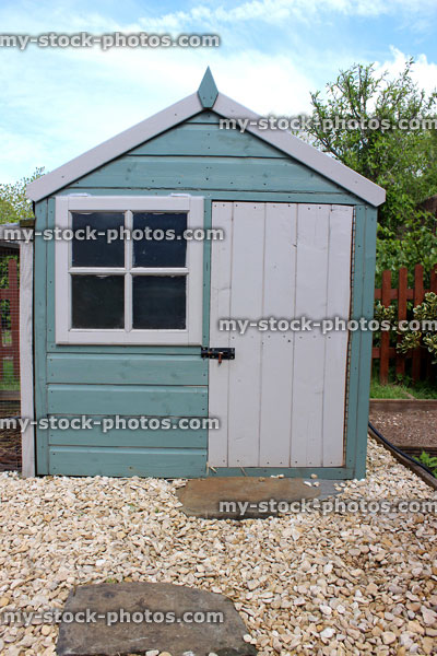 Stock image of wooden children's playhouse in garden setting, with stepping stone pathway