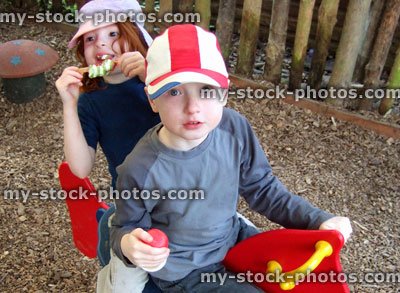 Stock image of boy and girl playing in children's playground, eating ice cream