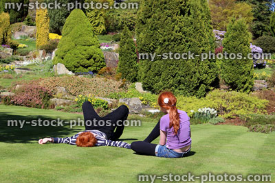 Stock image of two children relaxing on sunny lawn in garden 