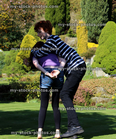 Stock image of brother and sister playing and wrestling in garden
