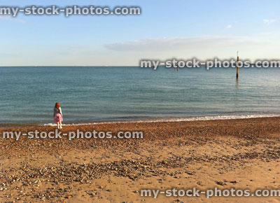 Stock image of girl throwing stones into sea on Portsmouth beach, England, UK