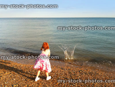 Stock image of girl throwing stones into sea on Portsmouth beach, England, UK