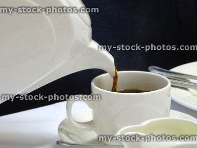 Stock image of pouring fresh black coffee, white coffee pot into cup / saucer / mug