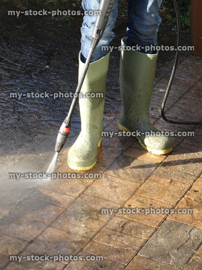 Stock image of boy wearing wellies hosing / pressure washing brick drive with powerwasher