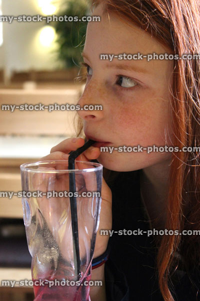 Stock image of young girl drinking blackcurrant fruit drink with straw