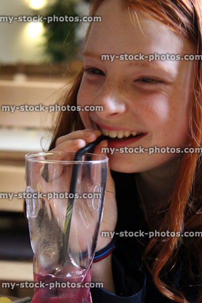 Stock image of happy young girl drinking from glass through straw