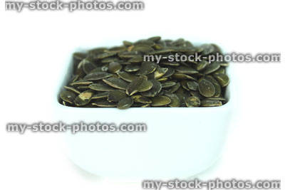 Stock image of pumpkin seeds / nuts, high protein healthy snack food, white dish