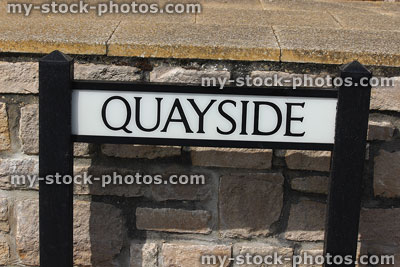 Stock image of quayside sign at roadside, by harbour / marina wall