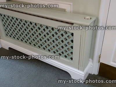 Stock image of wooden radiator cover / cabinet, fretwork grille painted green