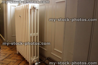 Stock image of old fashioned cast iron radiator on wooden floor