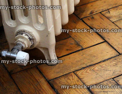 Stock image of old fashioned cast iron radiator on wooden floor