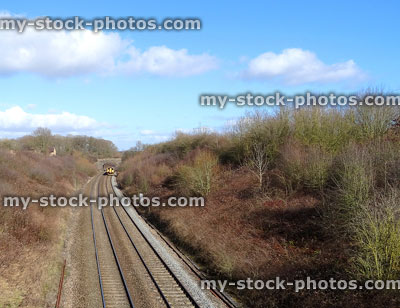 Stock image of railway line / railroad tracks, yellow diesel train engine