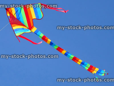 Stock image of arrowhead kite flying in sky with rainbow stripes