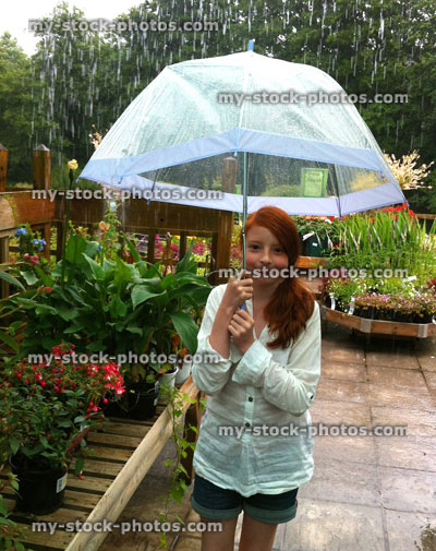Stock image of girl under an umbrella in a downpour at garden centre