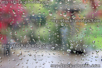 Stock image of rain drops on a window pane with a blurred garden view