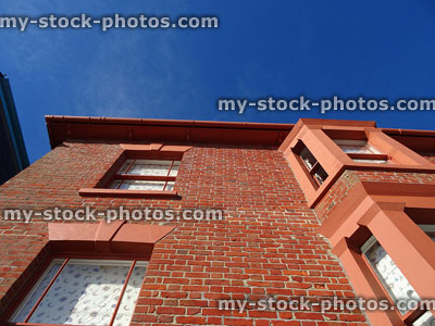 Stock image of looking up red brick house with bay windows