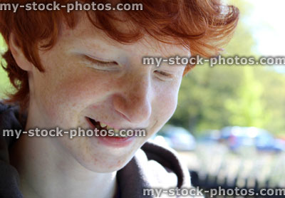 Stock image of happy boy with red hair smiling to himself
