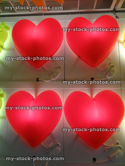 Stock image of four plastic red love heart lights illuminated from behind