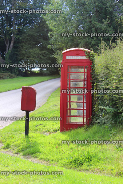 Stock image of old fashioned red telephone box in countryside village / phone booth / post box