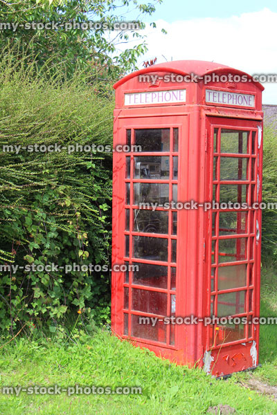 Stock image of old fashioned red telephone box in countryside village / English phone booth 