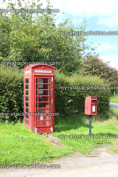 Stock image of old fashioned red telephone box in countryside village / phone booth / post box