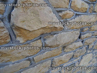 Stock image of repointed irregular stone wall, with grey cement / concrete