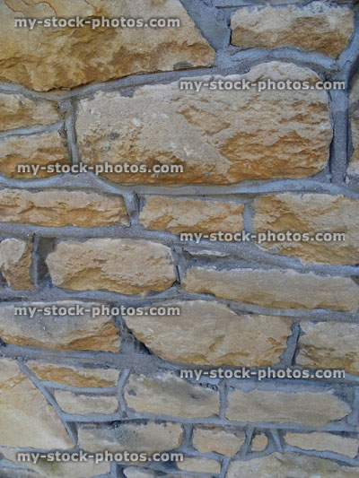 Stock image of irregular sandstone wall, repointed with grey cement mix