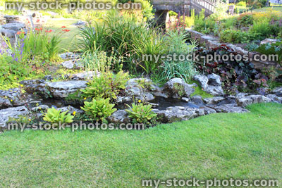 Stock image of landscaped rockery / rock garden with green lawn grass