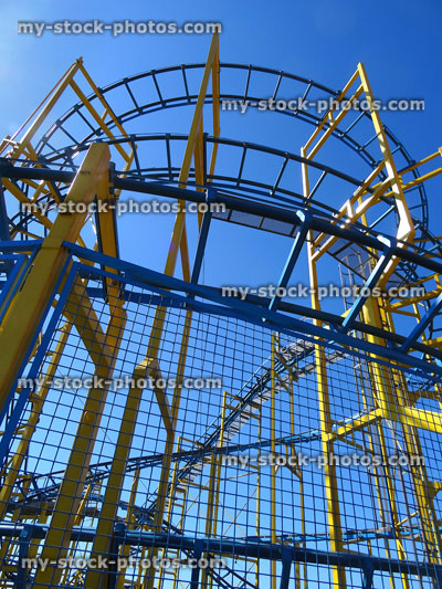 Stock image of rollercoaster train tracks and curves against blue sky