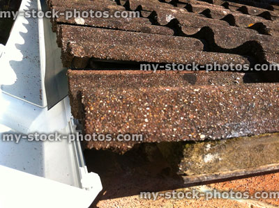 Stock image of clay roof tiles / new white UPVC plastic guttering