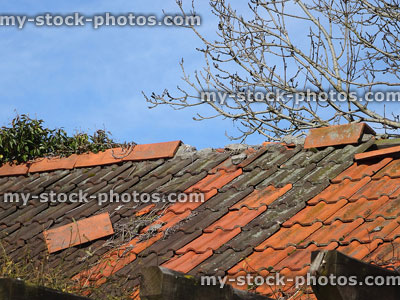 Stock image of damaged roof needing repair, falling loose tiles / ridge tiles