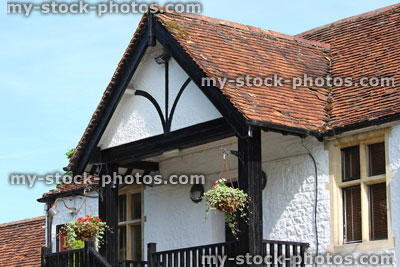Stock image of summer hanging baskets with flowers, outside white house in country