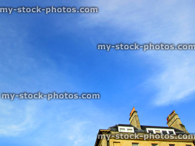 Stock image of rooftop and chimneys against blue sky with clouds