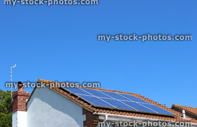 Stock image of solar panels on roof of house with sunny blue sky