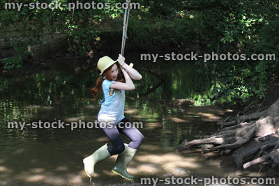 Stock image of girl on rope swing, swinging across river water