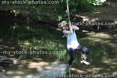 Stock image of girl on rope swing, swinging across river water