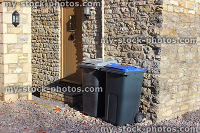 Stock image of grey rubbish bins by back door, recycling wheelie bins