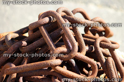 Stock image of rusty chain links piled up at seaside harbour